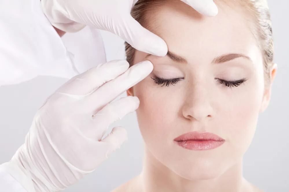 Der Kosmetiker untersucht die Haut um die Augen um die Augen